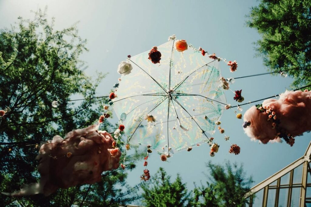 Decorated umbrella hanging outdoors with fluffy decorations.